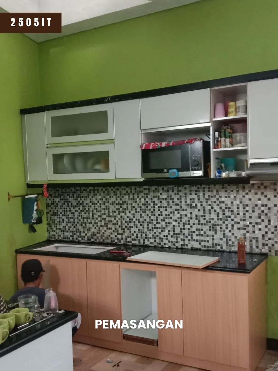 Tim Mebel Minimalis Bandung memasang kitchen set proyek 2505IT di Cileunyi Bandung, kabinet atas putih sudah terpasang dan kabinet bawah motif kayu sedang disetel